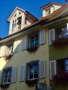 Casa amarilla con ventanas blancas con persianas y flores en Mittelalterhotel-Gästehaus Rauchfang en Meersburg