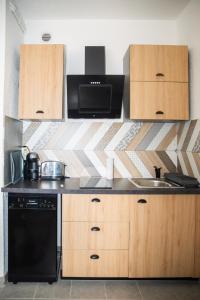cocina con armarios de madera y lavavajillas negro en le studio du Grazel, en Gruissan