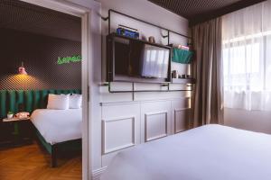a bedroom with two beds and a tv on a door at The ReMIX Hotel in Paris