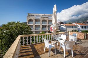 a balcony with white chairs and a table and an umbrella at Guest House Lotos in Becici