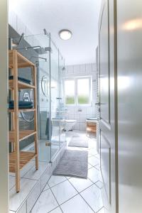 een badkamer met glazen wanden en witte tegelvloeren bij Ferienwohnung Leipzig Land in Naunhof