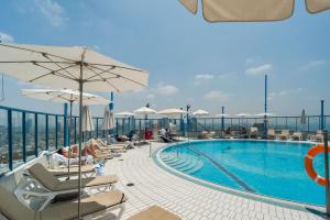 a swimming pool with chairs and umbrellas on a building at Picturesque 3BR Apt w Balcony & Parking Near Beach by Sea N' Rent in Tel Aviv