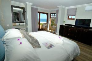 a bedroom with a white bed with a view of the ocean at Dolphin Dunes Guesthouse in Wilderness
