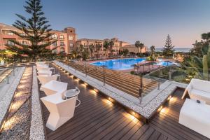 vistas a la piscina de un hotel con bancos y luces en Barceló Punta Umbría Mar en Punta Umbría