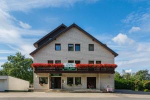 een groot bakstenen gebouw met rode bloemen erop bij Lohmann's Kapeller Hof in Langenfeld