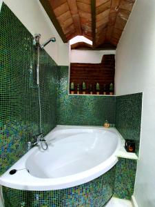 La salle de bains est pourvue d'une baignoire et de carrelage vert. dans l'établissement Almocabar Luxury Apartment, à Ronda