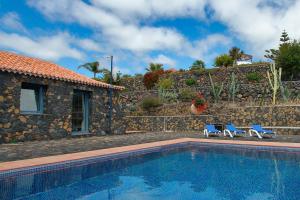 a swimming pool with two blue chairs and a house at Casa Amalia in Los Llanos de Aridane