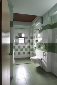 a bathroom with a toilet and green and white tiles at Sha Ri Loum Homestay in Shillong