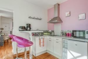 a kitchen with white cabinets and purple stools at Jolysable in Pons