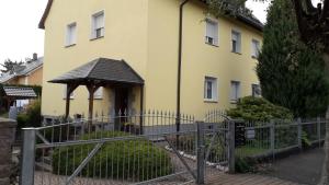 una casa gialla con recinzione e gazebo di Ferienwohnung Leipzig Land a Naunhof