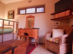 a bedroom with a bed and a desk and a chair at Swellendam Overnight Accommodation in Swellendam