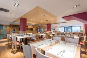 a dining room with white tables and chairs and a restaurant at Hotel Los Pasiegos in Hoznayo