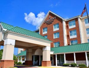 a front view of a hotel with an american flag at Country Inn & Suites by Radisson, Fredericksburg, VA in Fredericksburg