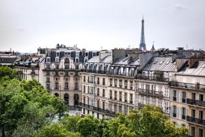 eine Gruppe von Gebäuden mit einem Turm im Hintergrund in der Unterkunft Hôtel Madeleine Plaza in Paris