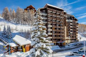 un hôtel dans la neige avec un sapin de Noël dans l'établissement Résidence Capfun Les Adrets, à Isola 2000