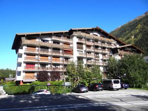 a large building with cars parked in a parking lot at Apartment Periades in Chamonix-Mont-Blanc