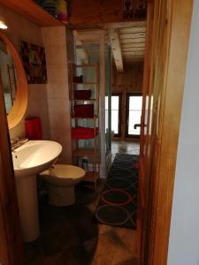 ein Badezimmer mit einem Waschbecken, einem WC und einem Regal in der Unterkunft Mansarda in Champorcher