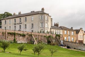 a large brick building with a grass field in front of it at The Talbot, Malton, North Yorkshire - The Coaching Inn Group in Malton