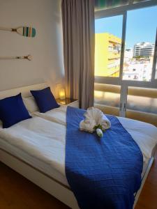1 dormitorio con 1 cama con manta azul y ventana en La Perla Apartment, en Torremolinos