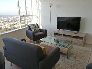 un soggiorno con TV, divano e sedia di Disa Park 14th Floor Apartment with City Views a Città del Capo