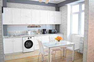 een keuken met witte kasten en een tafel met stoelen bij Boutique apartment in the center in Bisjkek