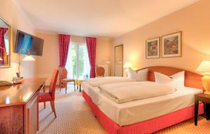 テンプリーンにあるホテル デルンゼー - ショルフハイデのベッド2台とデスクが備わるホテルルームです。