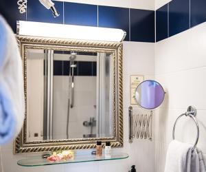 ein Badezimmer mit einem Spiegel und einem Waschbecken in der Unterkunft Hotel Ritzi in München