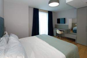 1 dormitorio con 1 cama blanca grande y escritorio en Buzë Boutique Hotel en Sarandë