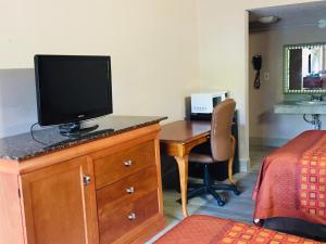 una camera da letto con scrivania e TV su un comò di Masters Inn a Seffner