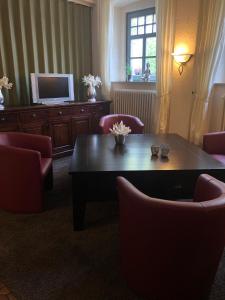 ein Wohnzimmer mit einem Tisch, Stühlen und einem TV in der Unterkunft Hotel Krone Post in Gersfeld