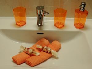 a bathroom sink with orange towels and glasses on it at Gästehaus Regina in Uderns