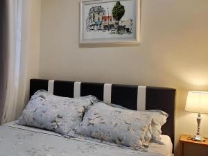 - un lit avec une tête de lit et des oreillers en noir et blanc dans l'établissement Jen's Paranaque City Apartment, à Manille