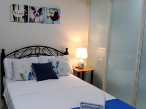 ein Schlafzimmer mit einem Bett und einer Lampe auf einem Tisch in der Unterkunft Jen's Paranaque City Apartment in Manila