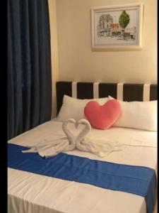 - un lit avec deux oreillers en forme de cœur dans l'établissement Jen's Paranaque City Apartment, à Manille
