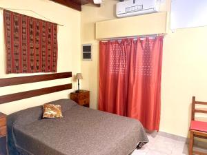 a bedroom with a bed and a red curtain at Puesto Las Totoras in San Antonio de Areco