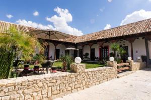 a stone wall in front of a house with an umbrella at Hotel Casa Delina in Comitán