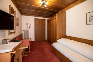 Habitación con cama, escritorio y TV. en Haus Gamberg, en Sankt Anton am Arlberg
