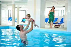 un homme tenant un bébé dans une piscine dans l'établissement Résidence Goélia Belle Epoque, à Mers-les-Bains