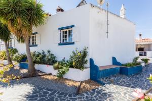 a white house with a blue bench and palm trees at Mértola Natural - Monte da Eirinha in Mértola