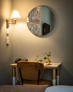 a mirror on a wall above a table with a chair at Lady Hamilton Hotel in Stockholm