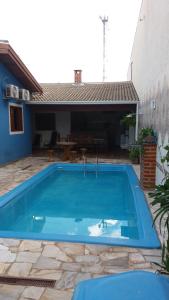 a large blue swimming pool in front of a house at Raízes Hotel in Cajobi