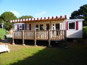 a tiny house with a porch and a deck at Camping les charmettes- in Les Mathes