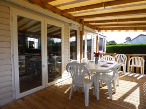a patio with a table and chairs on a deck at Camping les charmettes- in Les Mathes