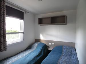 a bedroom with two beds and a window at Camping les charmettes- in Les Mathes