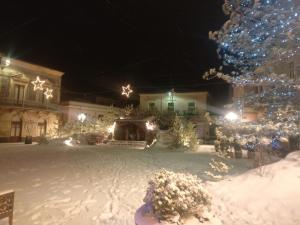 a yard covered in snow with a christmas tree and lights at Il Noccioleto in Linguaglossa