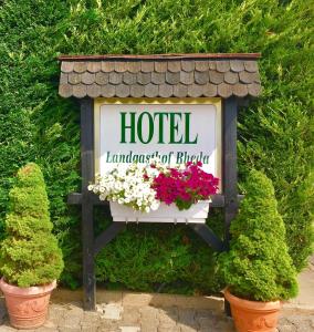 a sign for a hotel with flowers in pots at Landgasthof Rheda Hotel - Restaurant in Rheda-Wiedenbrück