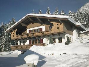 a house covered in snow with a pile of snow at Landhaus Patricia in Ellmau