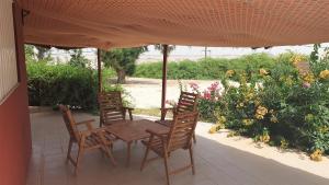 una mesa de madera y sillas bajo una sombrilla en el patio en Diamarek Hotel Sur La Plage, en Saint-Louis