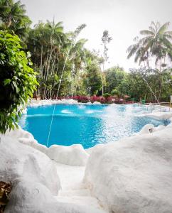 a swimming pool with blue water in a resort at Hosteria El Paraiso de las Orquideas in Archidona