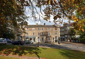 um grande edifício de tijolos com carros estacionados em frente em The Old Sweet Factory em Harrogate